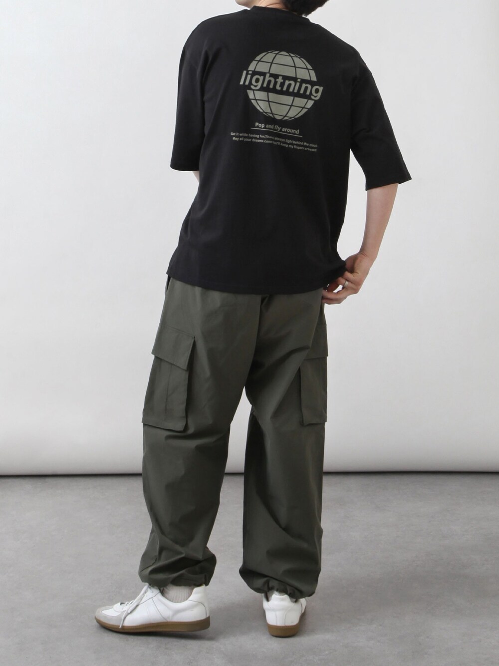 ブラック系のTシャツ/カットソー、グリーン系のカーゴパンツ、ホワイト系のスニーカーを着用したメンズの春コーディネートの1枚目の写真