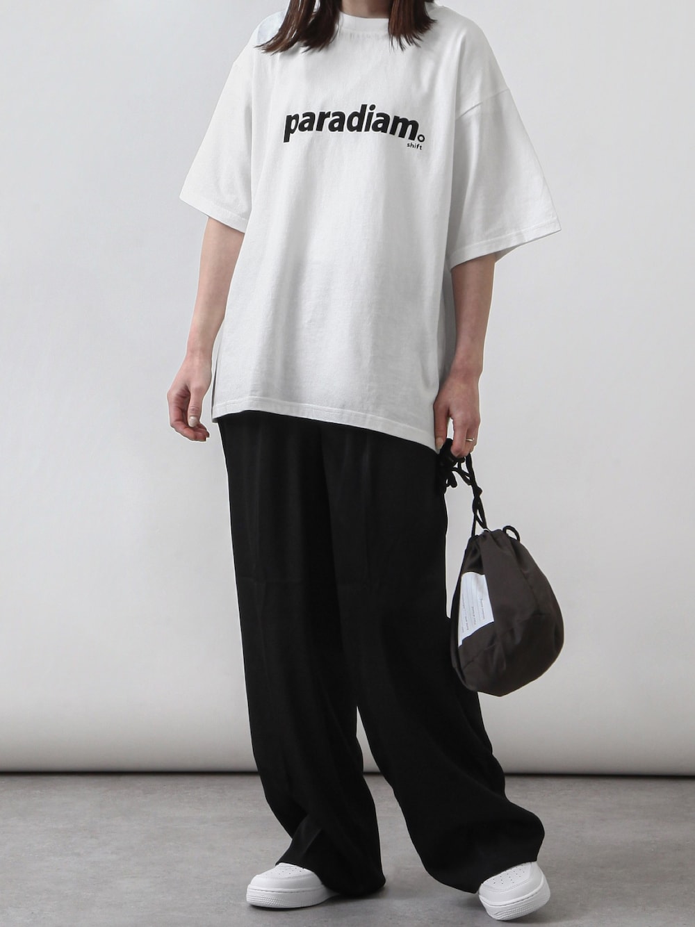 ホワイト系のTシャツ/カットソー、ブラック系のスラックス、ホワイト系のスニーカーを着用したレディースの春コーディネートの1枚目の写真