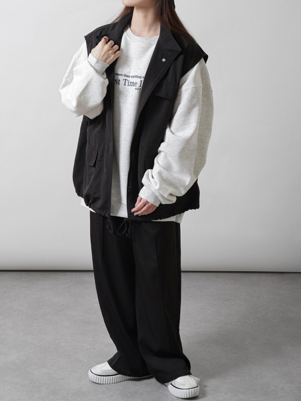 グレー系のスウェット、ブラック系のスラックスを着用したレディースの秋コーディネートの1枚目の写真