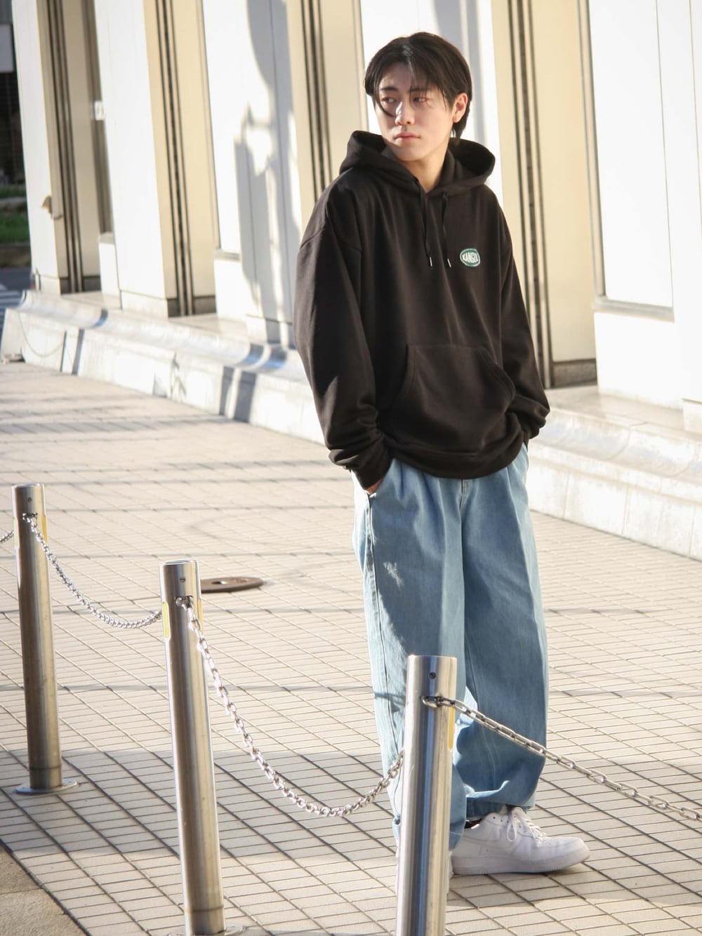 ブラック系のパーカー、ブルー系のデニムパンツ、ホワイト系のスニーカーを着用したメンズの秋コーディネートの1枚目の写真