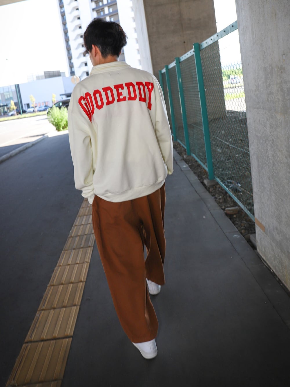 ホワイト系のスウェット、ブラウン系のチノパンツ、ホワイト系のスニーカーを着用したメンズの秋コーディネートの1枚目の写真