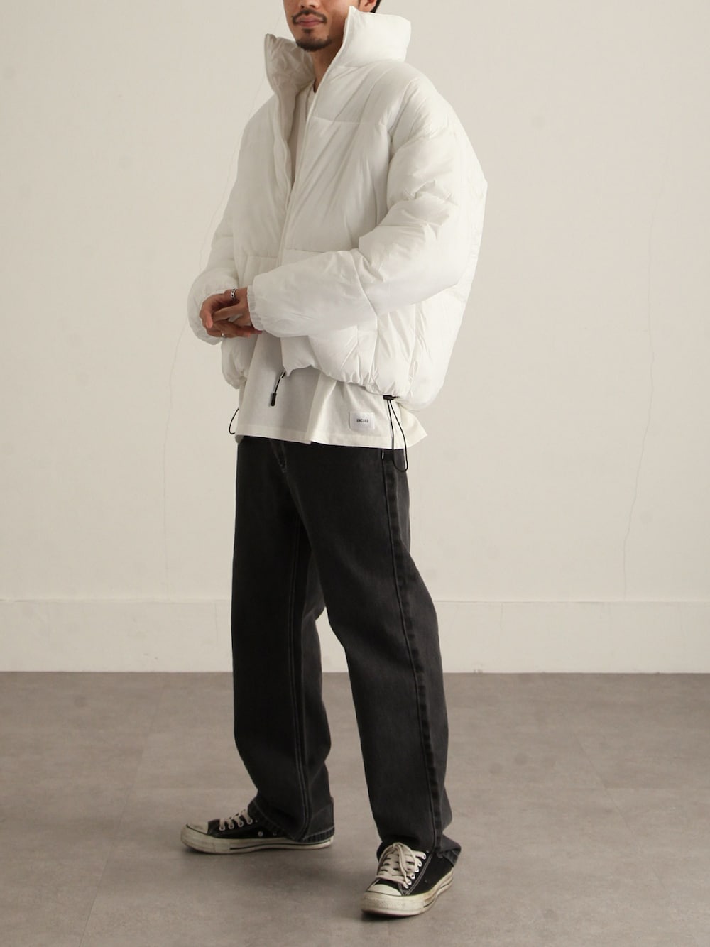 ホワイト系のダウンジャケット/コート、ホワイト系のTシャツ/カットソー、ブラック系のデニムパンツを着用したメンズの秋コーディネートの1枚目の写真