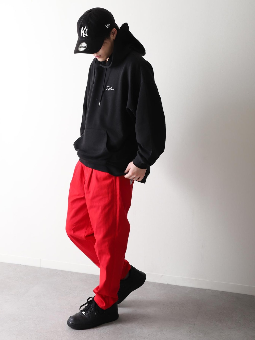 ブラック系のパーカー、レッド系のチノパンツ、ブラック系のスニーカーを着用したメンズの冬コーディネートの1枚目の写真