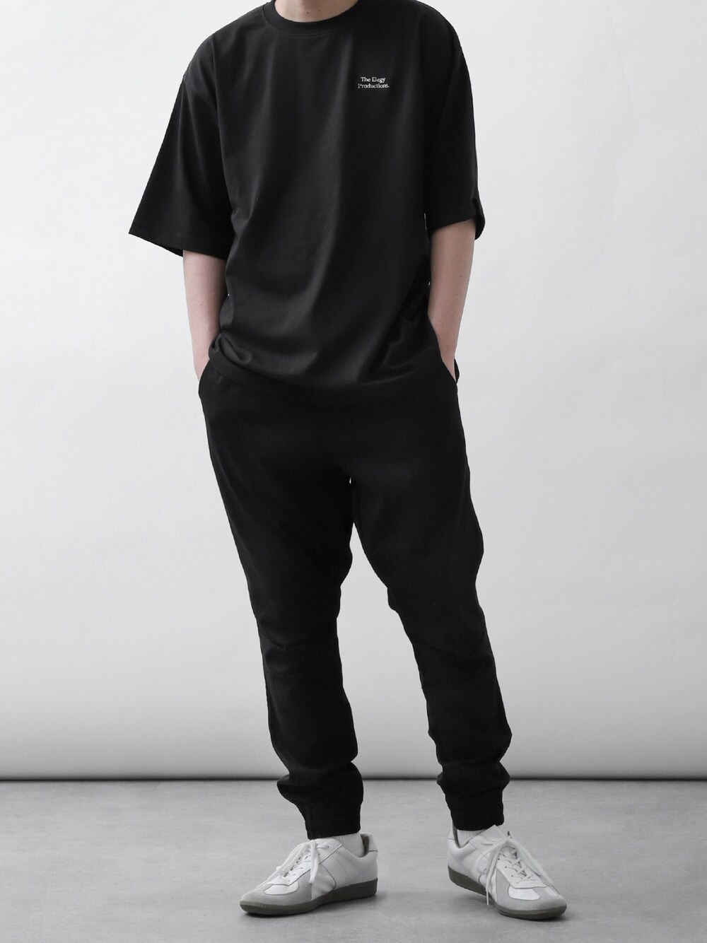 ブラック系のTシャツ/カットソー、ブラック系のスウェットパンツ、ホワイト系のスニーカーを着用したメンズの夏コーディネートの1枚目の写真