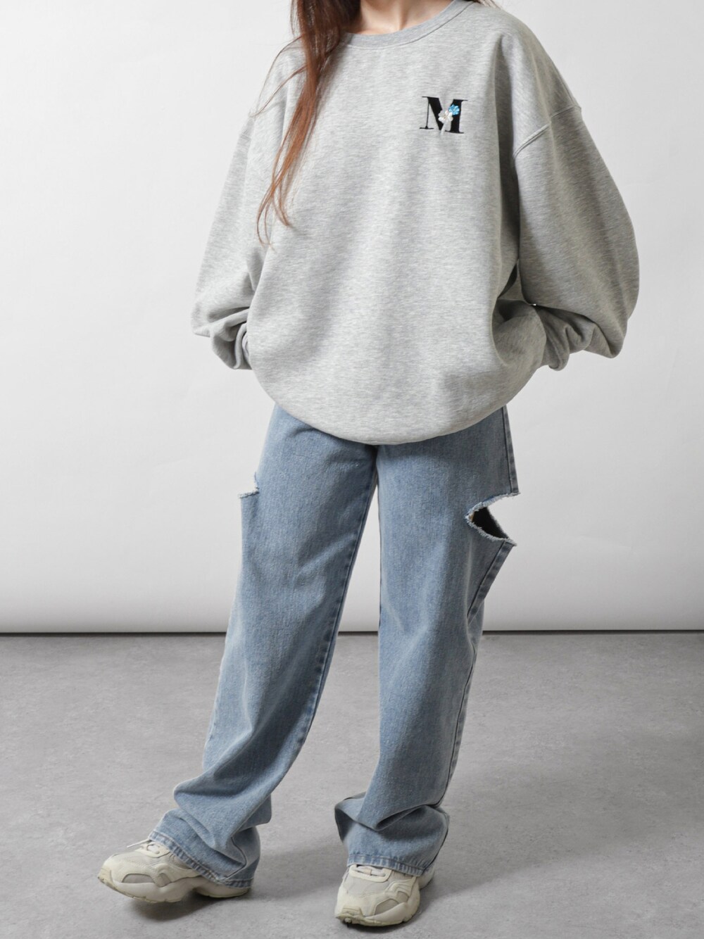 グレー系のスウェット、ブルー系のデニムパンツ、ベージュ系のスニーカーを着用したレディースの秋コーディネートの1枚目の写真