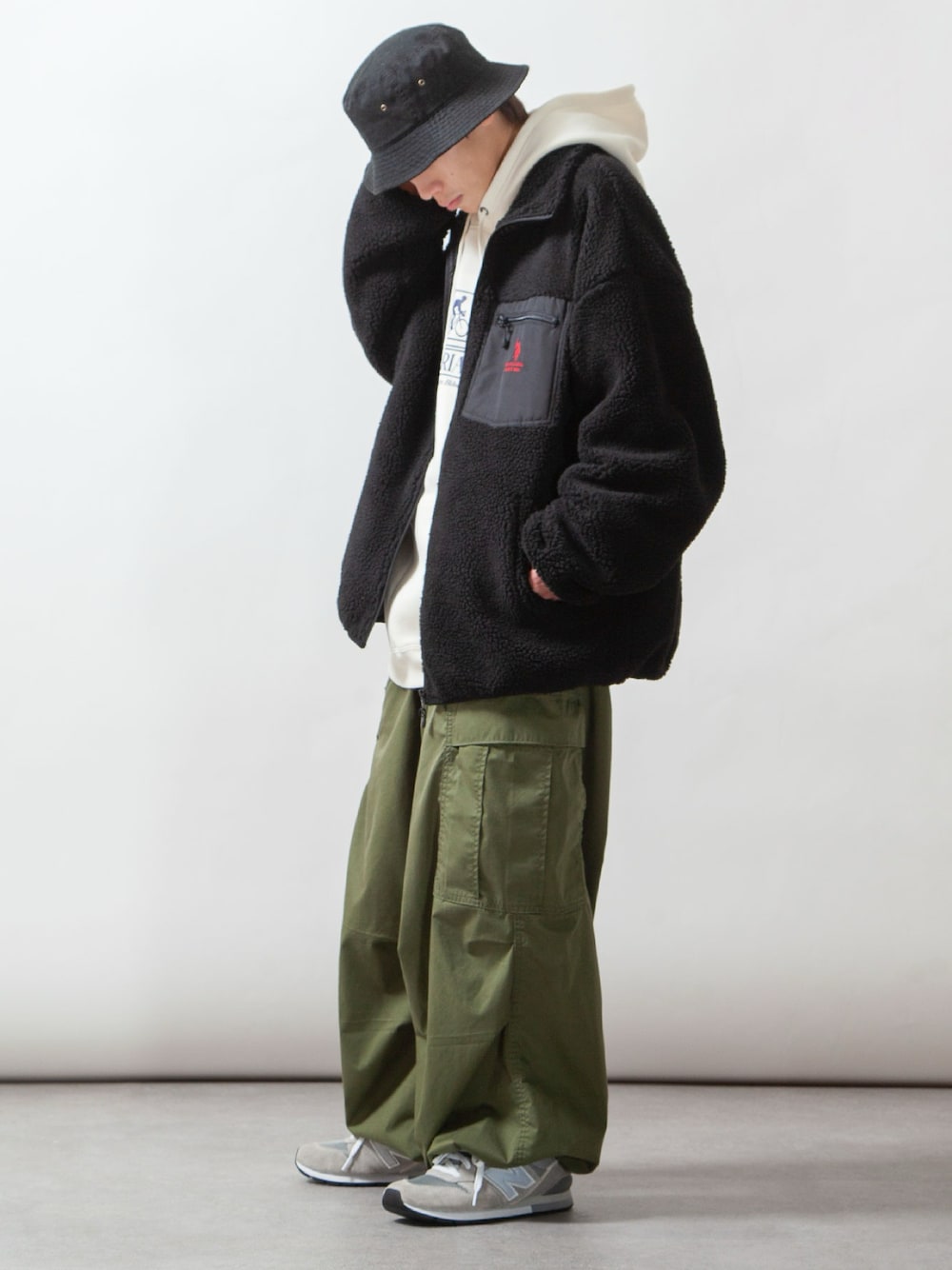 ブラック系のブルゾン、ホワイト系のパーカー、グリーン系のカーゴパンツを着用したメンズの冬コーディネートの1枚目の写真