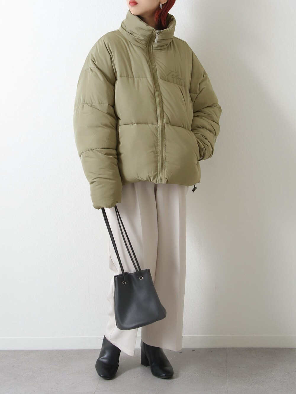 グリーン系のダウンジャケット/コート、ベージュ系のスラックス、ブラック系のブーツを着用したレディースの冬コーディネートの1枚目の写真