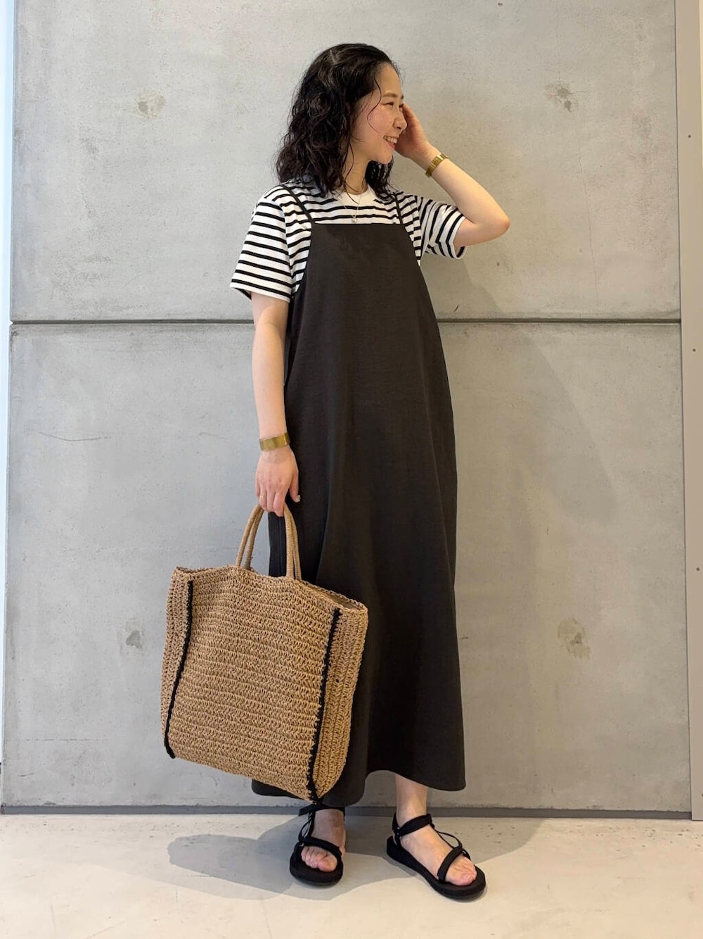 ベージュ系のトートバッグ、ホワイト系のTシャツ/カットソー、ブラック系のサンダルを着用したレディースの夏コーディネートの1枚目の写真