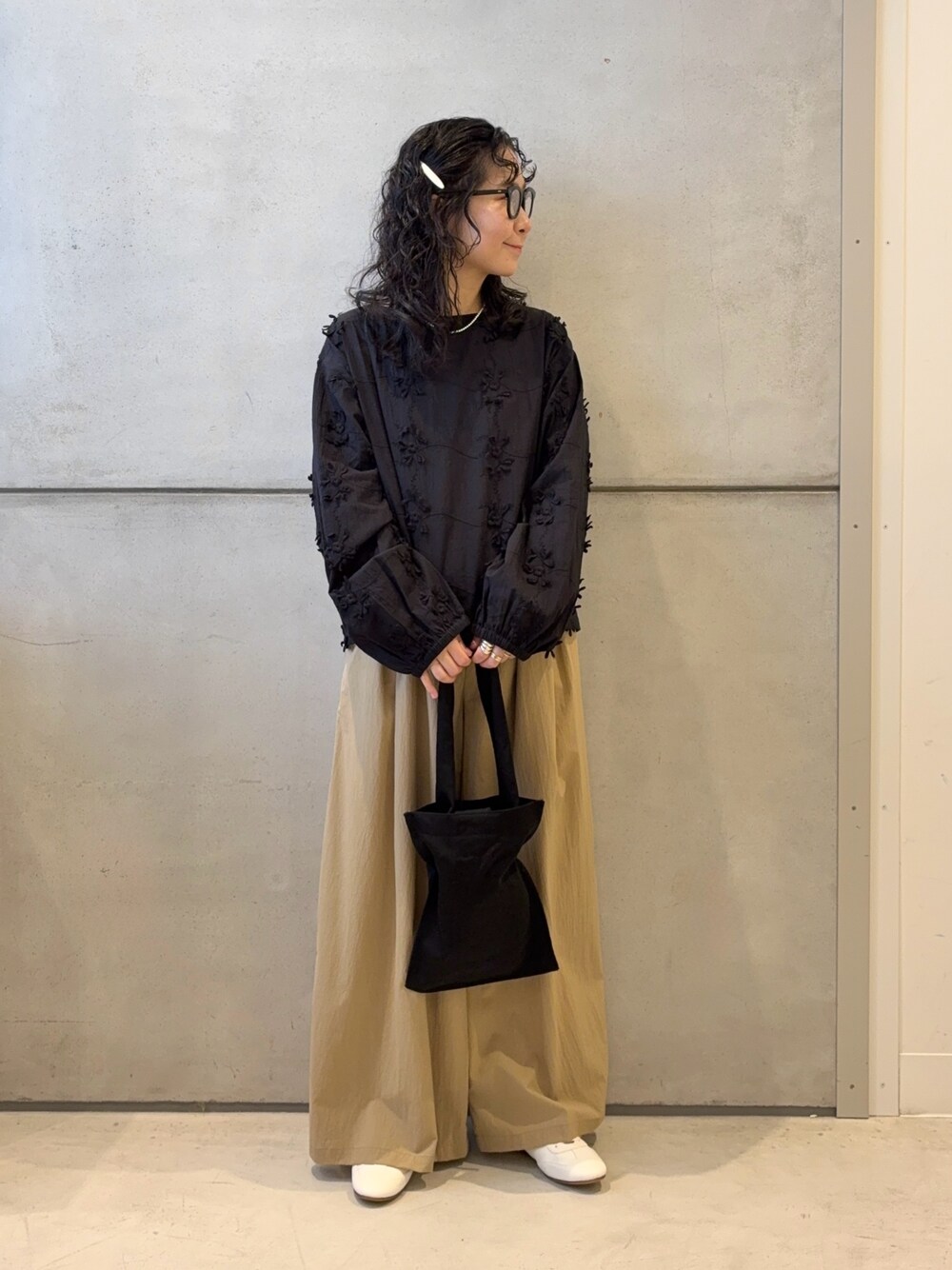 ベージュ系のその他パンツ、ブラック系のトートバッグ、ホワイト系のスニーカーを着用したレディースの春コーディネートの1枚目の写真