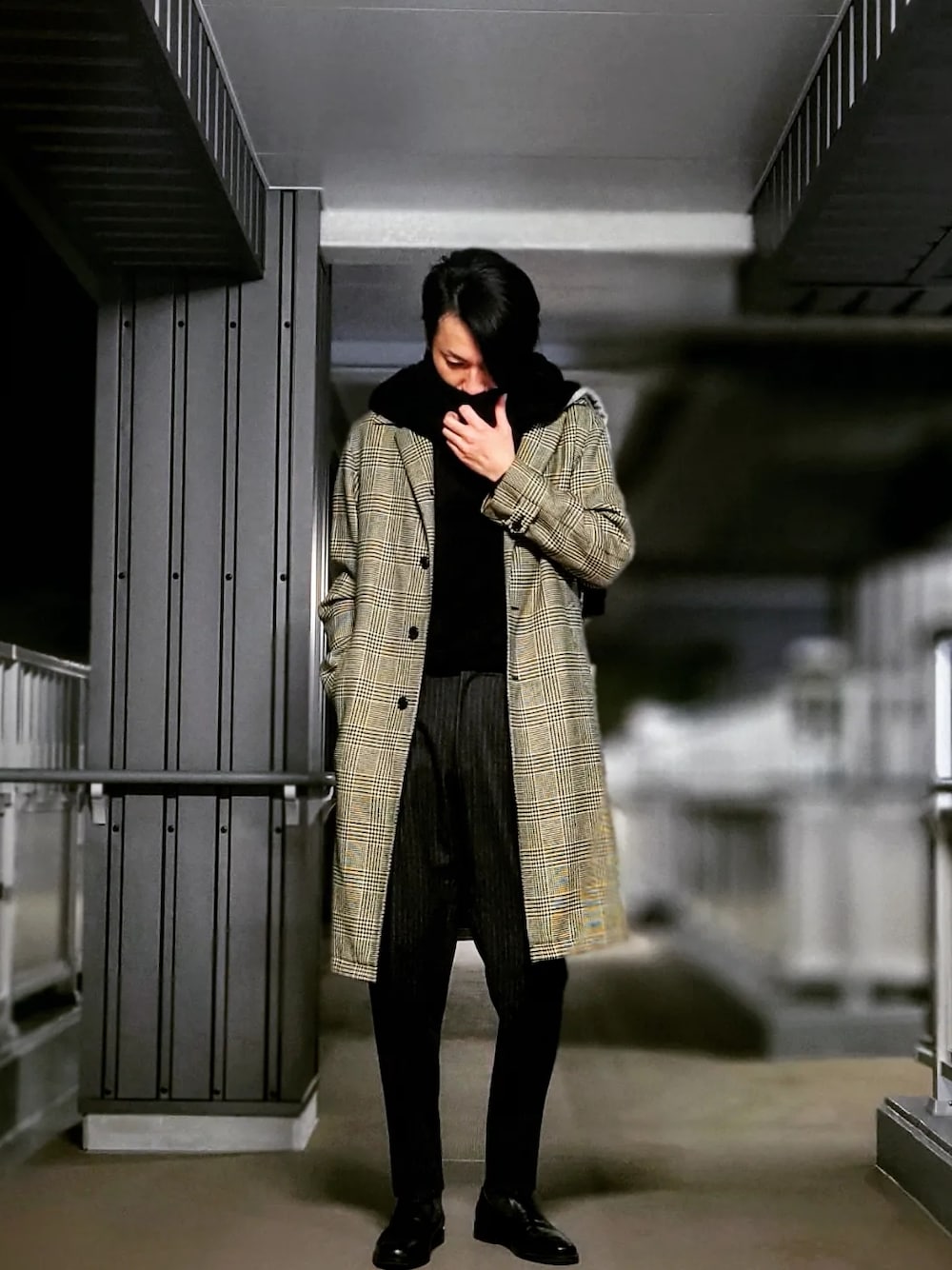 グレー系のスラックス、ブラック系のドレスシューズ、グレー系のステンカラーコートを着用したメンズの春コーディネートの2枚目の写真