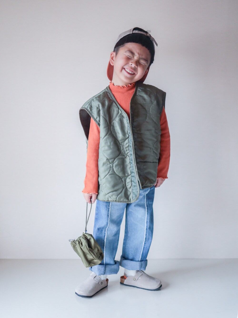 ブルー系のデニムパンツ、オレンジ系のTシャツ/カットソー、ベージュ系のサンダルを着用したキッズの春コーディネートの1枚目の写真