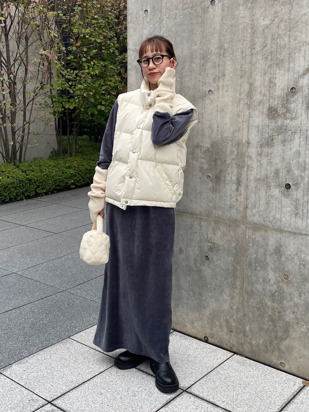 ブラック系のブーツ、ホワイト系のショルダーバッグ、ブラック系のメガネを着用したレディースの秋コーディネートの1枚目の写真