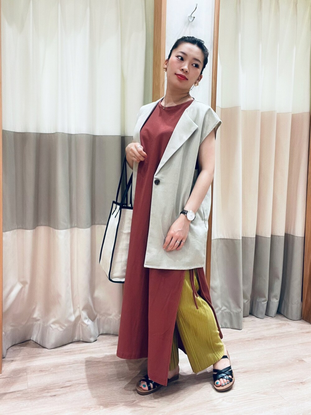 レッド系のワンピース、ベージュ系のベスト、ベージュ系のトートバッグを着用したレディースの夏コーディネートの1枚目の写真