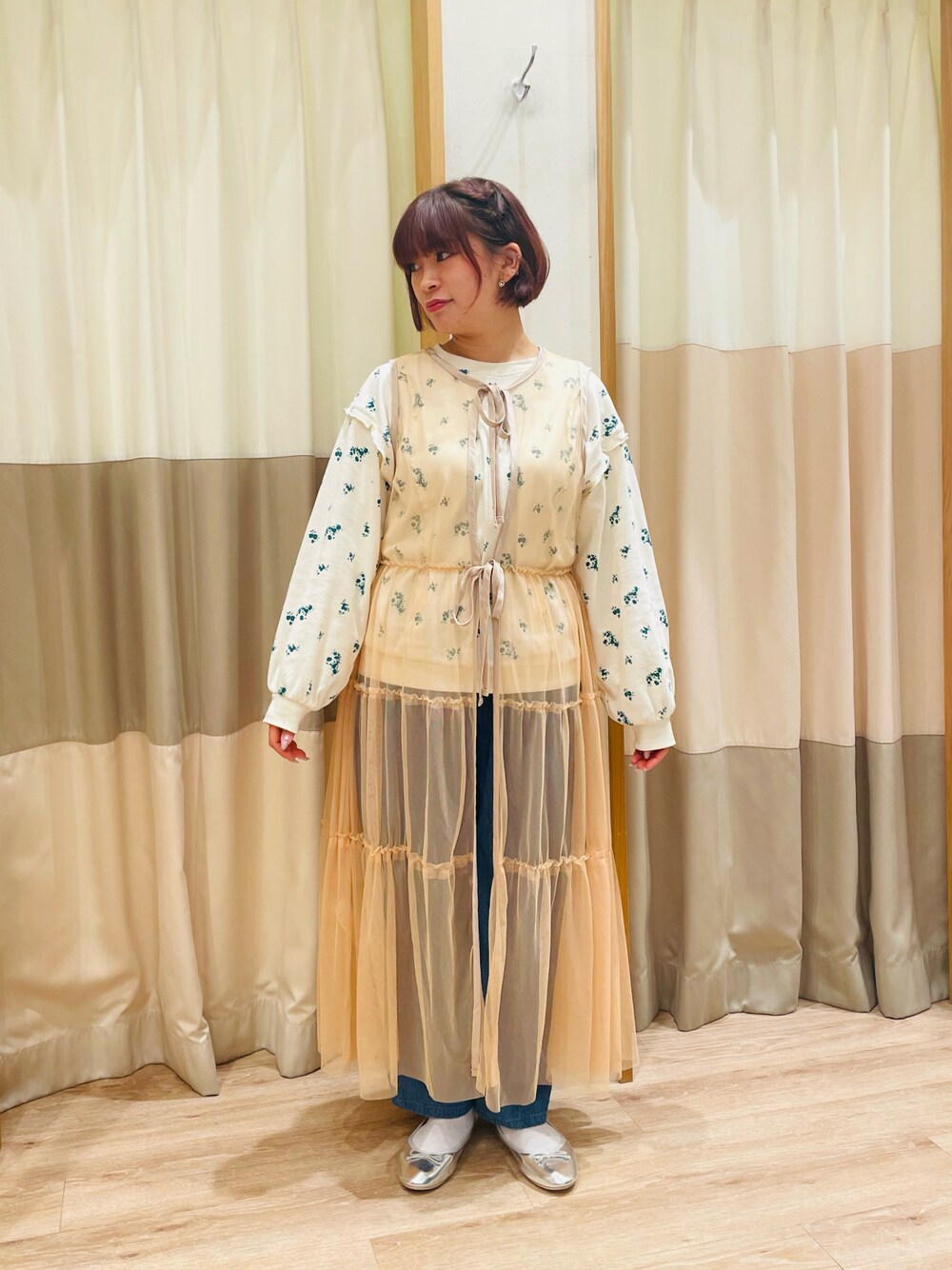 グリーン系のTシャツ/カットソー、オレンジ系のワンピース、ブルー系のデニムパンツを着用したレディースの春コーディネートの1枚目の写真