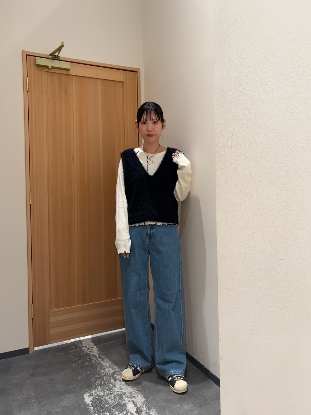 ブラック系のベスト、ホワイト系のTシャツ/カットソー、ブルー系のデニムパンツを着用したレディースの秋コーディネートの1枚目の写真