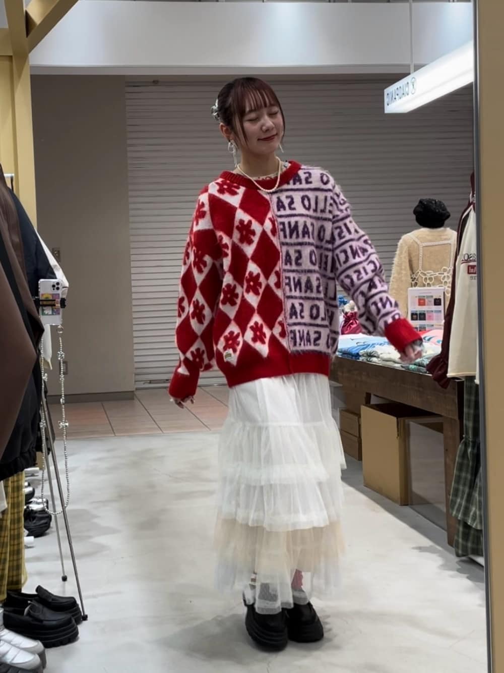 レッド系のニット/セーター、ホワイト系のスカート、ブラック系のパンプスを着用したレディースの冬コーディネートの1枚目の写真