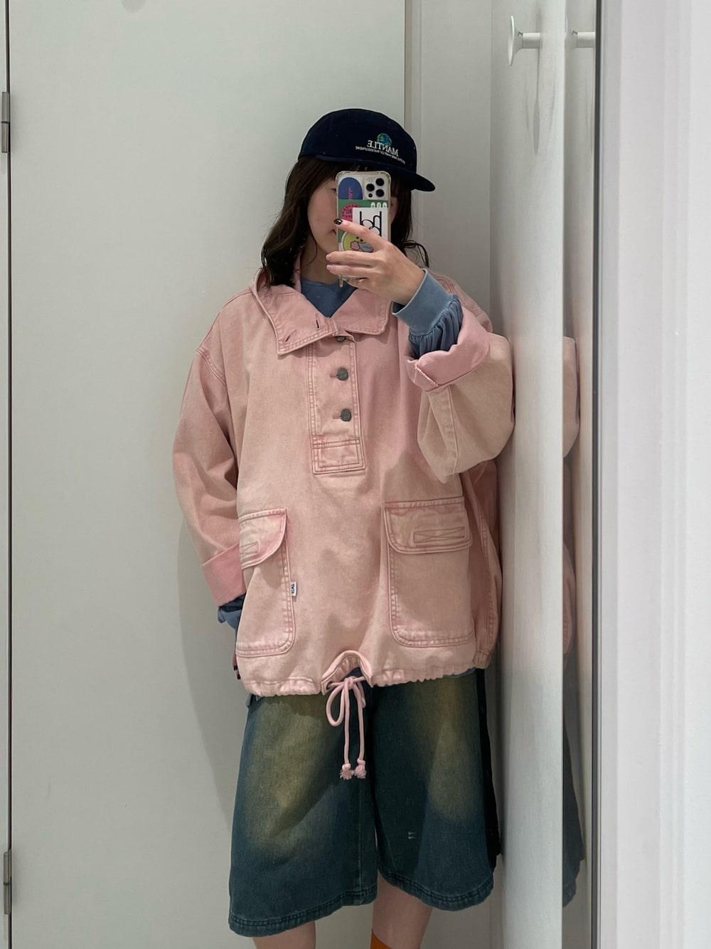 ピンク系のブルゾン、ブルー系のキャップを着用したレディースの秋コーディネートの1枚目の写真