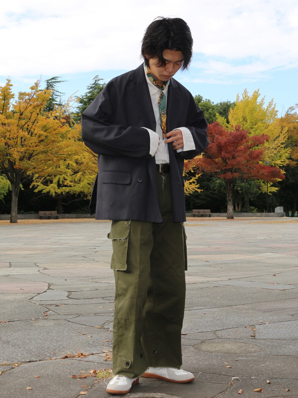 グレー系のテーラードジャケット、グリーン系のカーゴパンツ、ホワイト系のスニーカーを着用したメンズの秋コーディネートの1枚目の写真