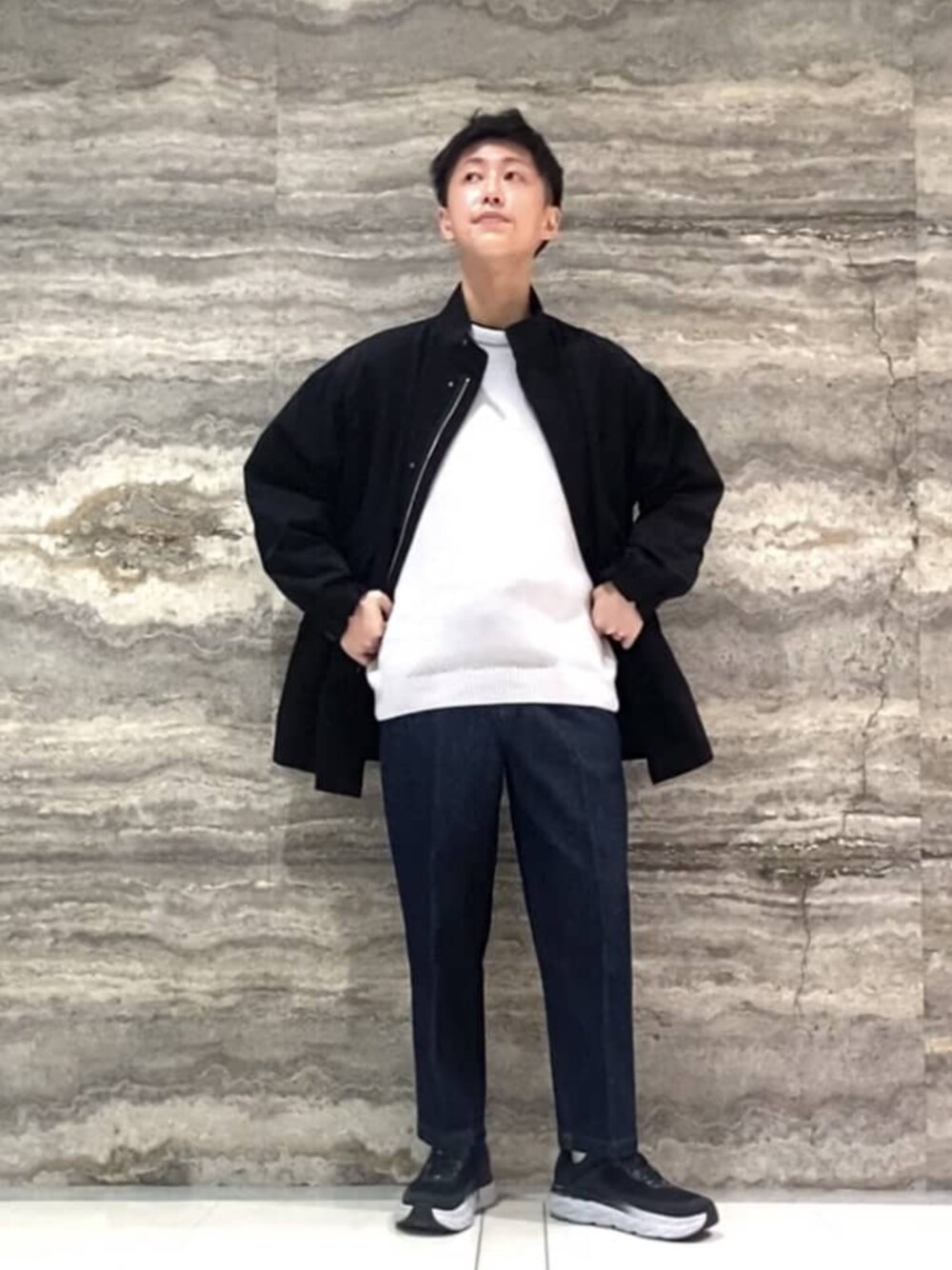 ブルー系のデニムパンツ、グレー系のニット/セーター、ブラック系のナイロンジャケットを着用したメンズの冬コーディネートの1枚目の写真