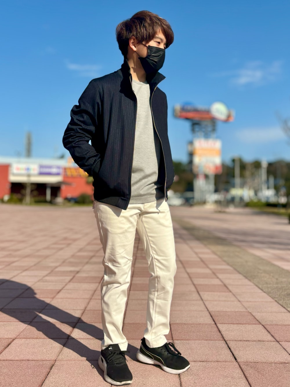黒のスタンドカラーブルゾンと白パンツを合わせた爽やかなメンズコーディネート