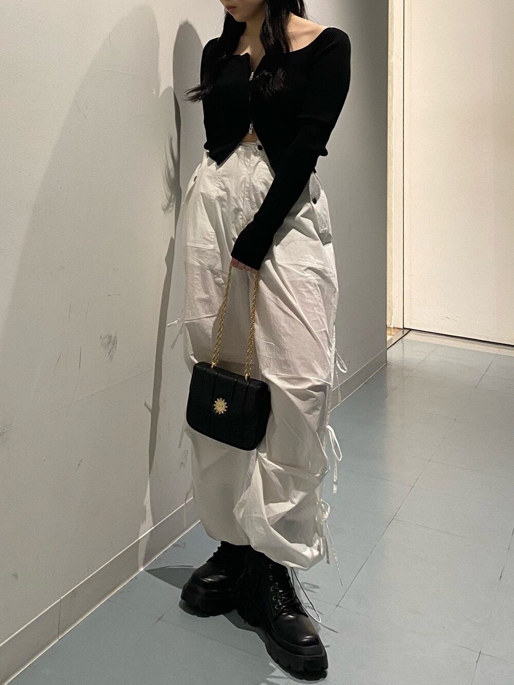 ブラック系のニット/セーター、ホワイト系のその他パンツ、ブラック系のブーツを着用したレディースの夏コーディネートの1枚目の写真