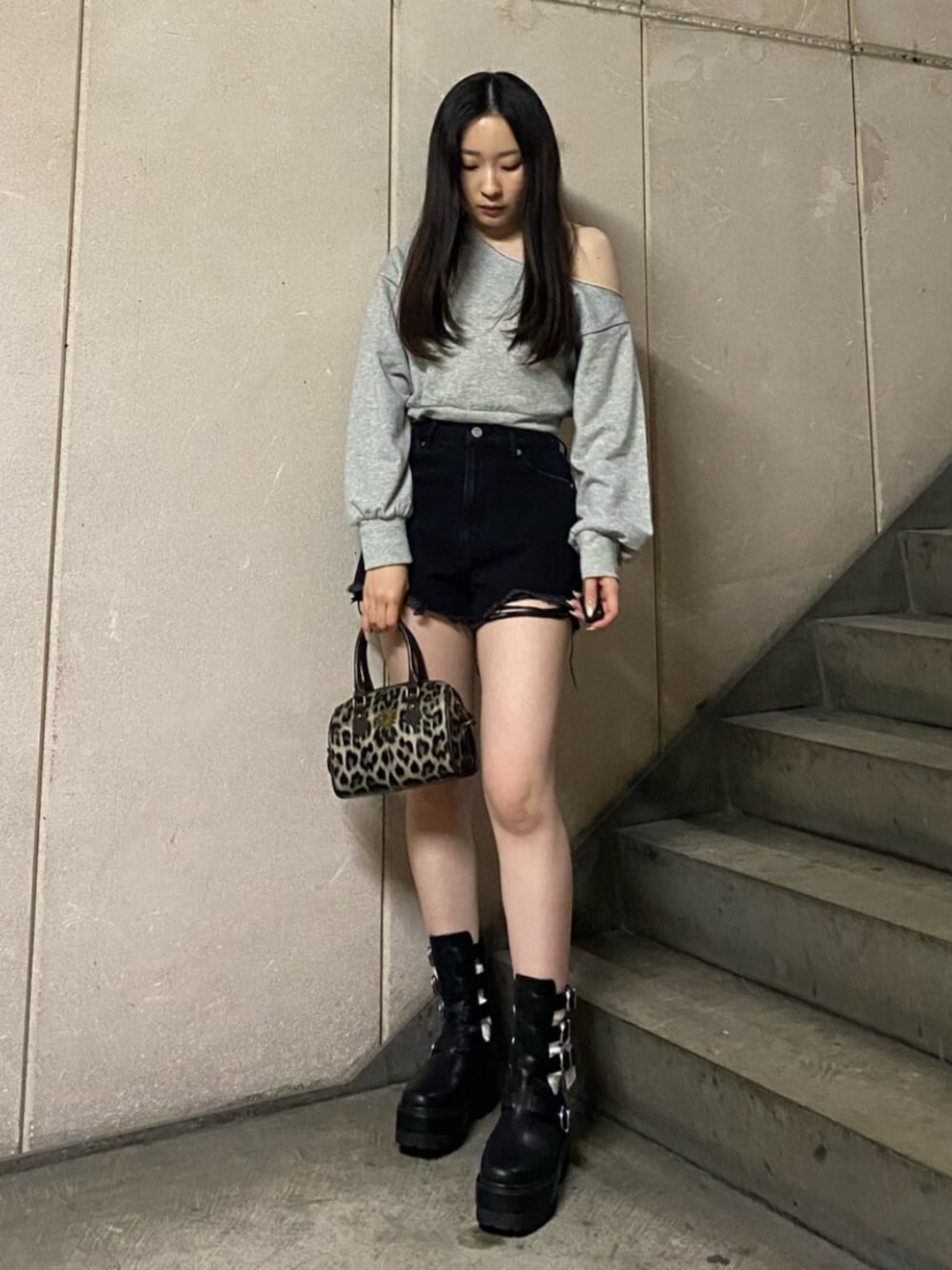 ブラック系のデニムパンツ、グレー系のスウェット、ブラック系のブーツを着用したレディースの春コーディネートの1枚目の写真