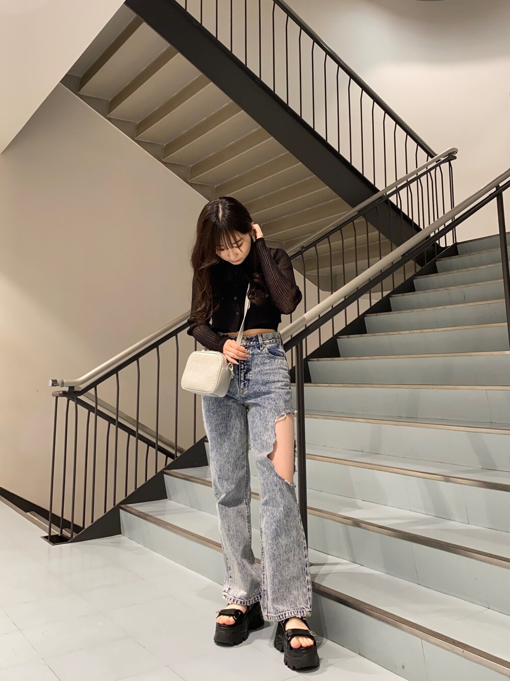 ブラック系のカーディガン/ボレロ、ブルー系のデニムパンツ、ブラック系のサンダルを着用したレディースの春コーディネートの1枚目の写真