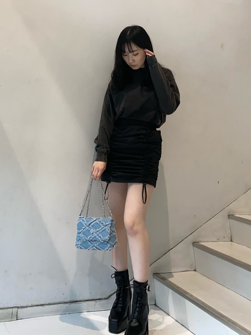 グレー系のTシャツ/カットソー、ブラック系のスカート、ブルー系のショルダーバッグを着用したレディースの冬コーディネートの1枚目の写真