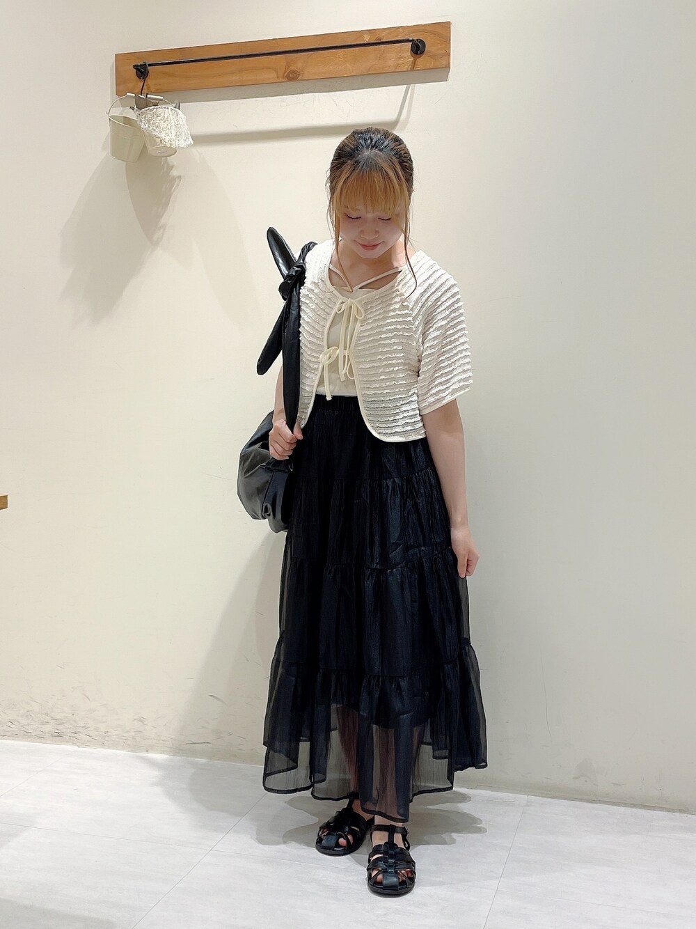 ホワイト系のカーディガン/ボレロ、ホワイト系のタンクトップ、ブラック系のハンドバッグを着用したレディースの夏コーディネートの1枚目の写真