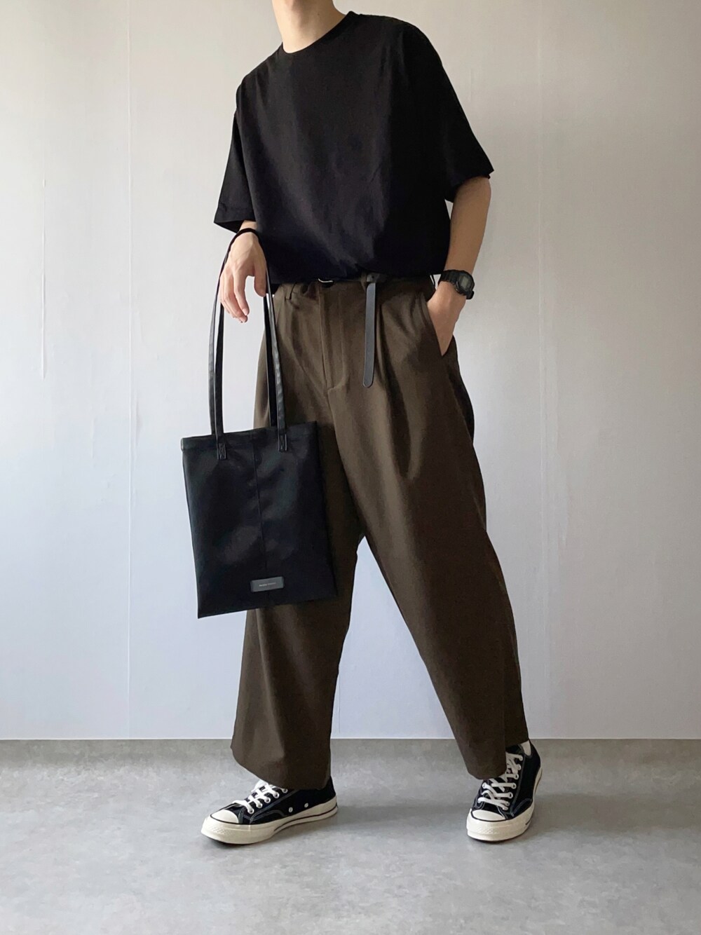 ブラック系のTシャツ/カットソー、グレー系のスラックス、ブラック系のスニーカーを着用したメンズの夏コーディネートの1枚目の写真