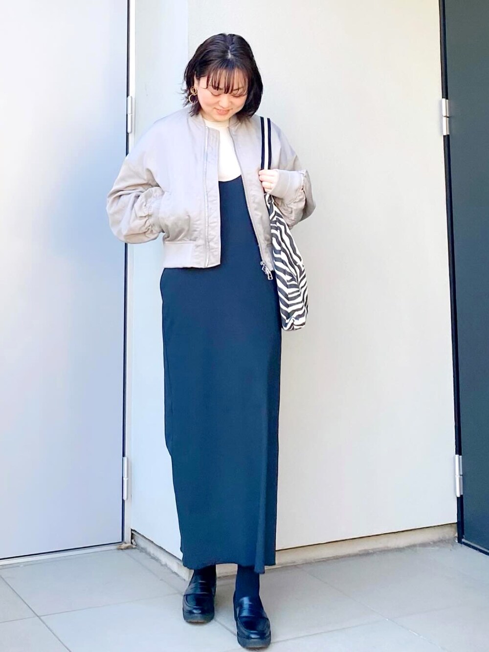 ブラック系のローファー、ブラック系のワンピース、グレー系のMA-1を着用したレディースの冬コーディネートの1枚目の写真