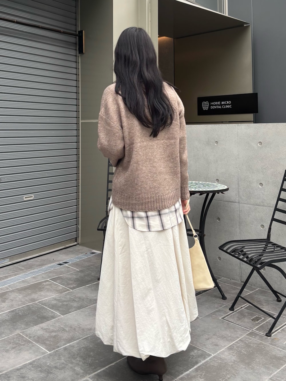 ブラウン系のニット/セーター、ホワイト系のシャツ/ブラウス、ホワイト系のスカートを着用したレディースの秋コーディネートの1枚目の写真