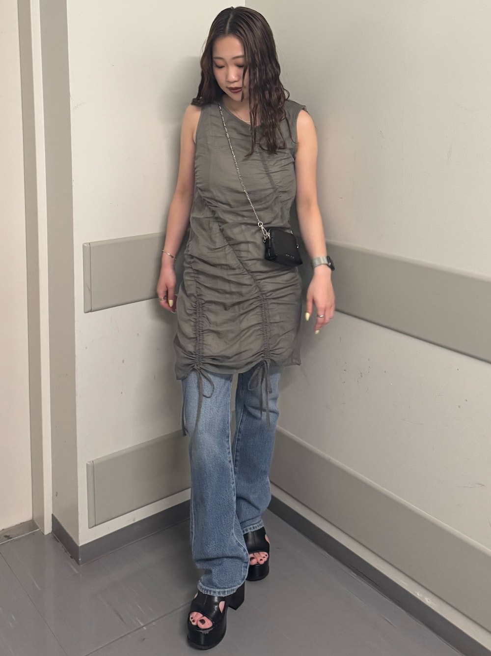 グレー系のワンピース、ブルー系のデニムパンツ、ブラック系のサンダルを着用したレディースの夏コーディネートの1枚目の写真