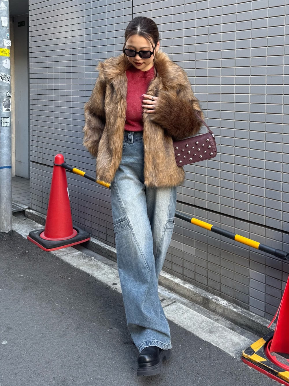 ブルー系のデニムパンツ、レッド系のニット/セーター、ブラウン系のその他アウターを着用したレディースの冬コーディネートの1枚目の写真
