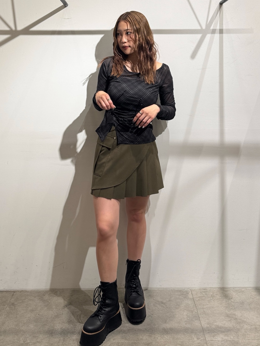 グリーン系のスカート、ブラック系のTシャツ/カットソー、ブラック系のブーツを着用したレディースの夏コーディネートの1枚目の写真