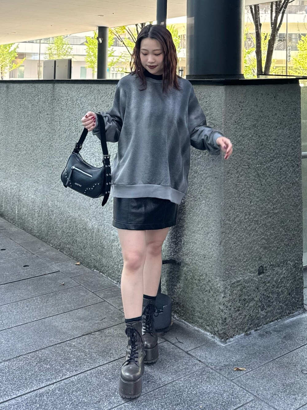 グレー系のスウェット、ブラック系のスカート、ブラック系のハンドバッグを着用したレディースの秋コーディネートの1枚目の写真