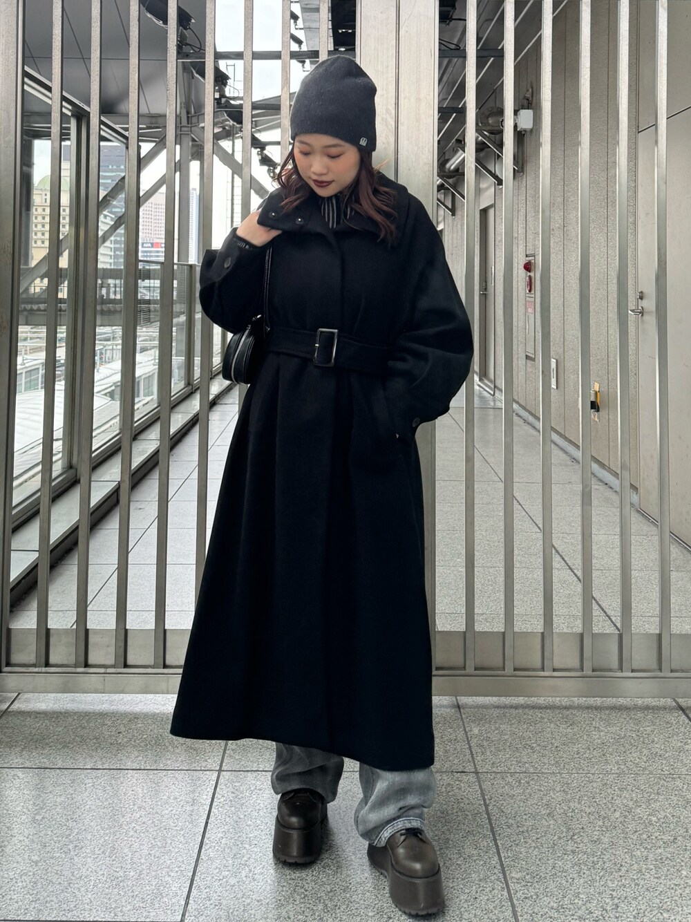 ブラック系のその他アウター、ブラック系のニット/セーター、ブラック系のデニムパンツを着用したレディースの秋コーディネートの1枚目の写真