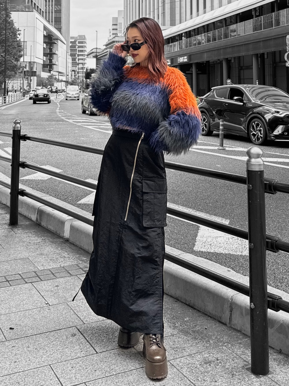 オレンジ系のニット/セーター、ブラック系のスカート、ブラウン系のブーツを着用したレディースの秋コーディネートの1枚目の写真