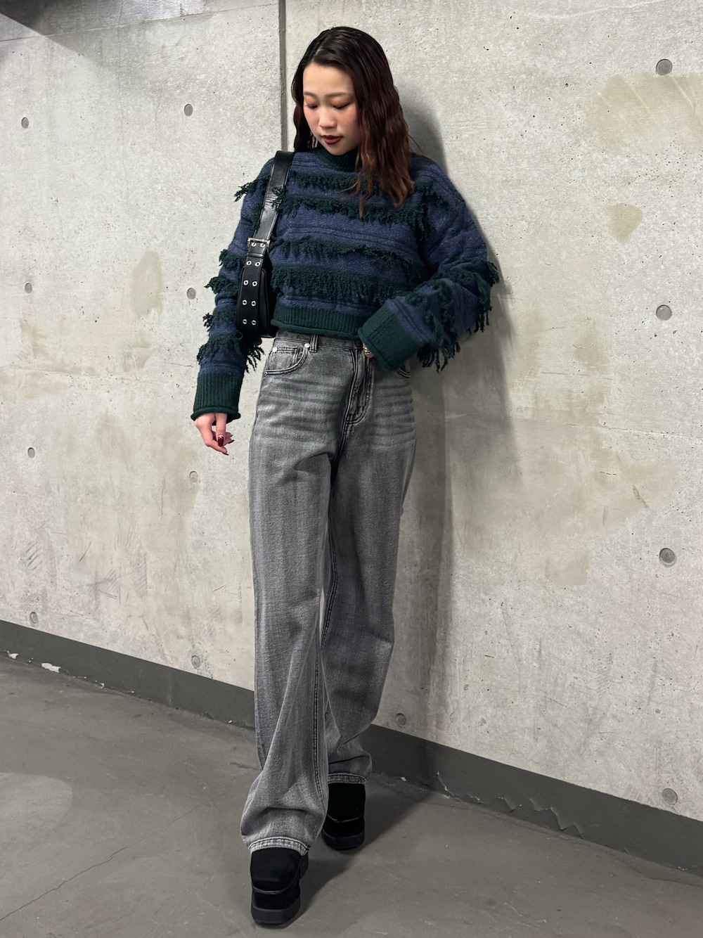 グリーン系のニット/セーター、ブラック系のデニムパンツ、ブラック系のブーツを着用したレディースの冬コーディネートの1枚目の写真
