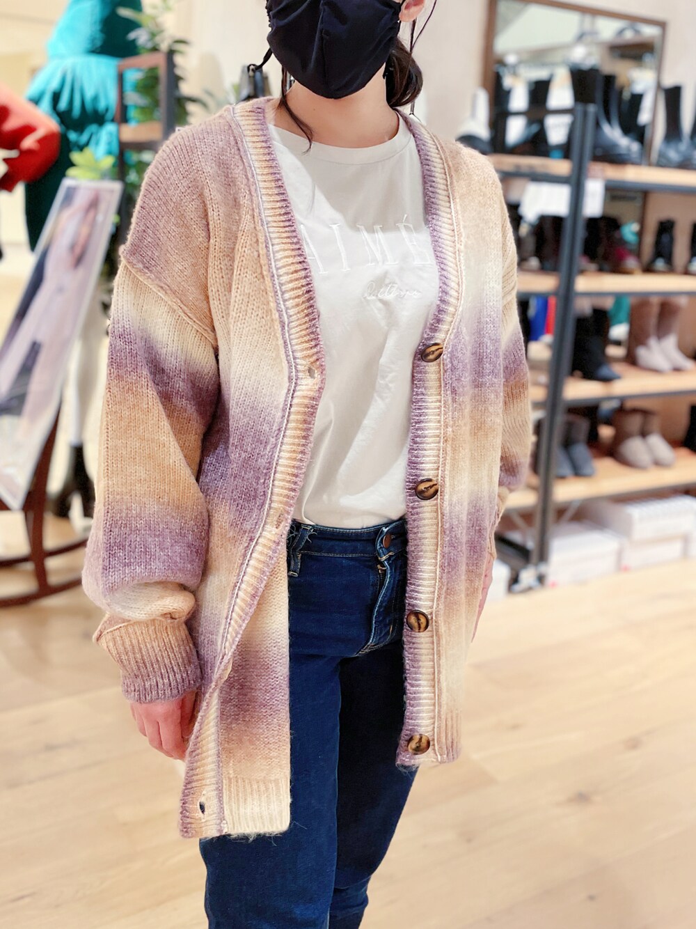 グレー系のTシャツ/カットソー、オレンジ系のカーディガン/ボレロ、ブルー系のデニムパンツを着用したレディースの秋コーディネートの1枚目の写真