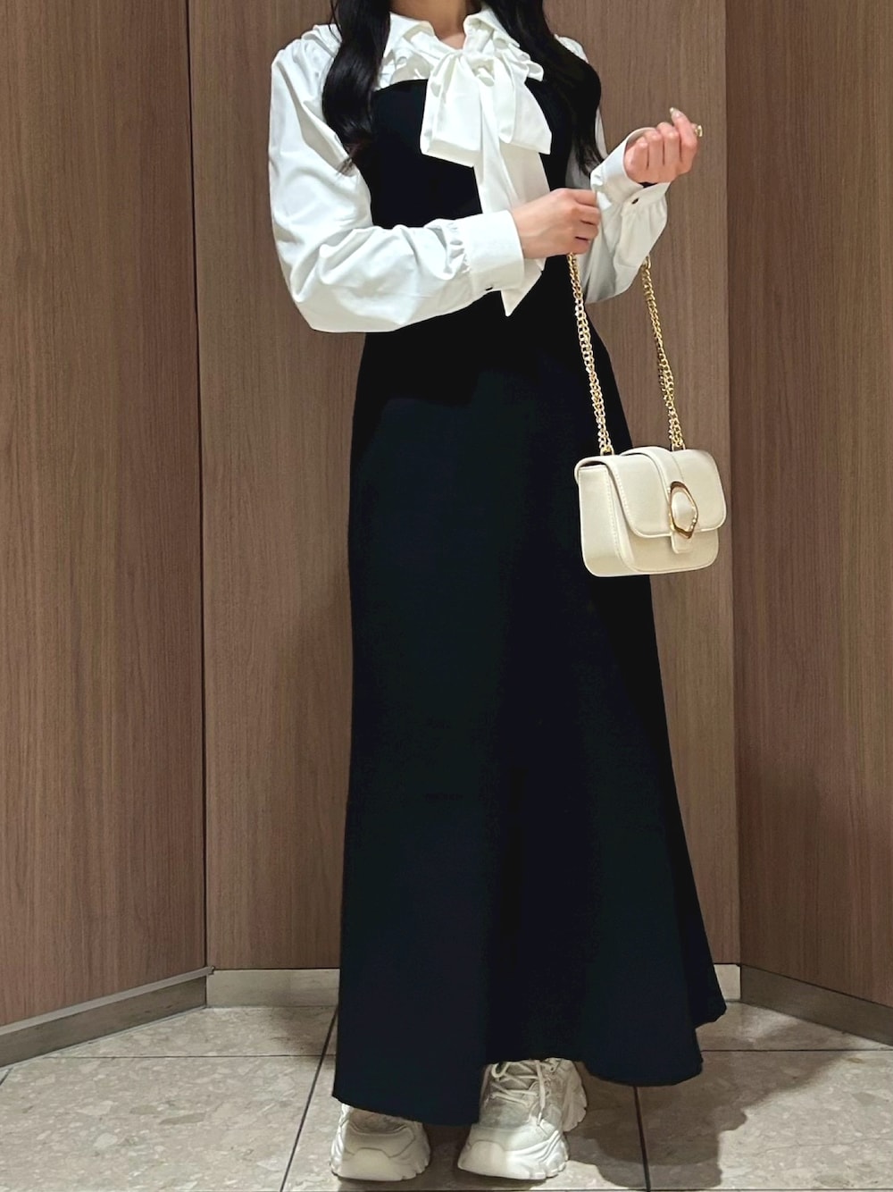 ホワイト系のショルダーバッグ、ブラック系のワンピース、ベージュ系のスニーカーを着用したレディースの冬コーディネートの1枚目の写真