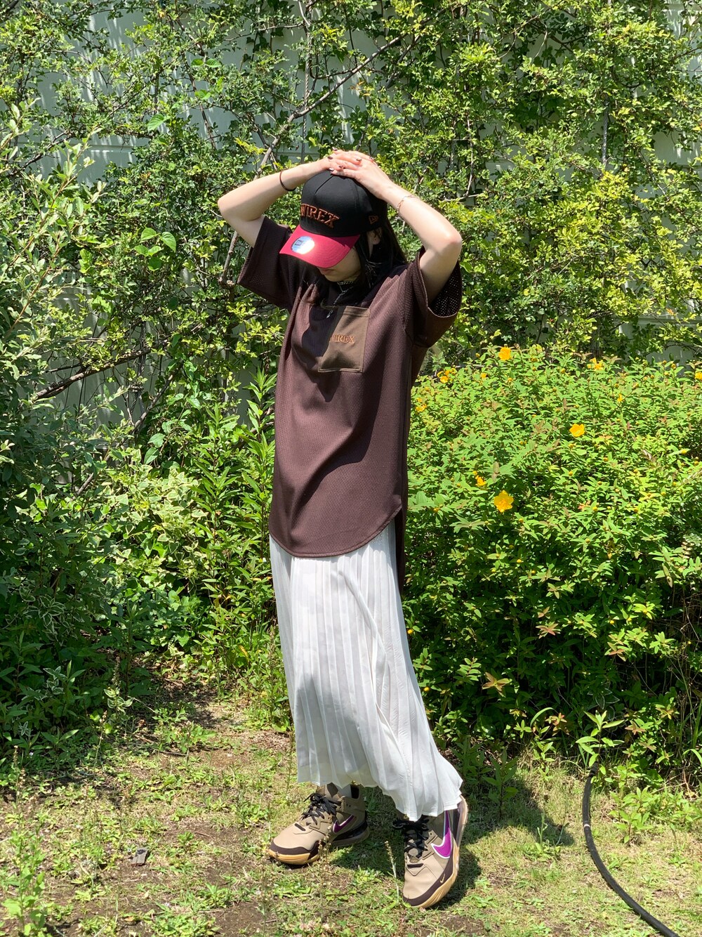ブラウン系のTシャツ/カットソー、ホワイト系のスカート、レッド系のキャップを着用したレディースの春コーディネートの1枚目の写真
