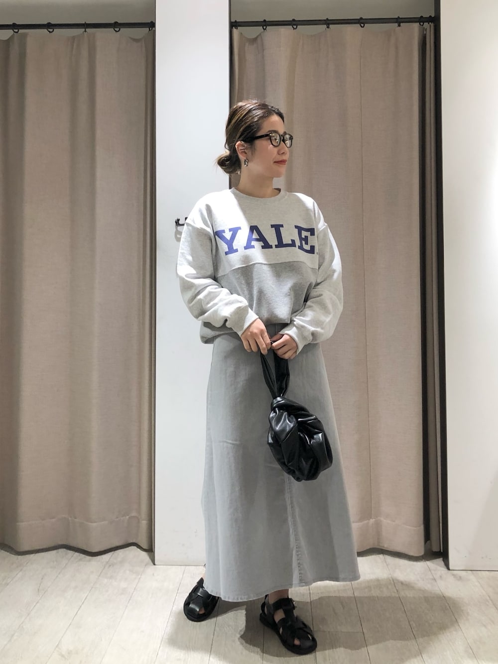 グレー系のスウェット、シルバー系のデニムスカート、ブラック系のハンドバッグを着用したレディースの春コーディネートの1枚目の写真