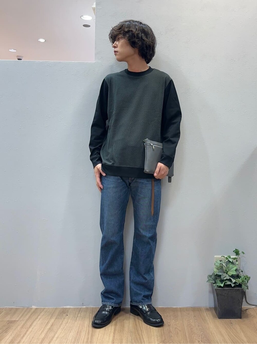 ブルー系のデニムパンツ、グレー系のクラッチバッグを着用したメンズの秋コーディネートの1枚目の写真