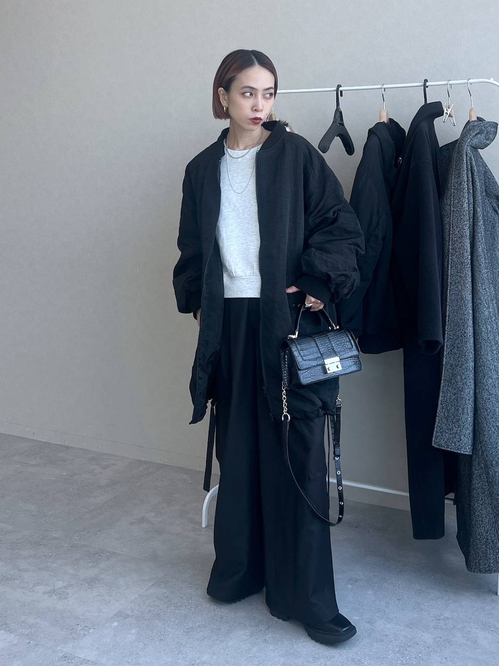 ブラック系のハンドバッグ、ブラック系のスラックス、ブラック系のブルゾンを着用したレディースの秋コーディネートの1枚目の写真