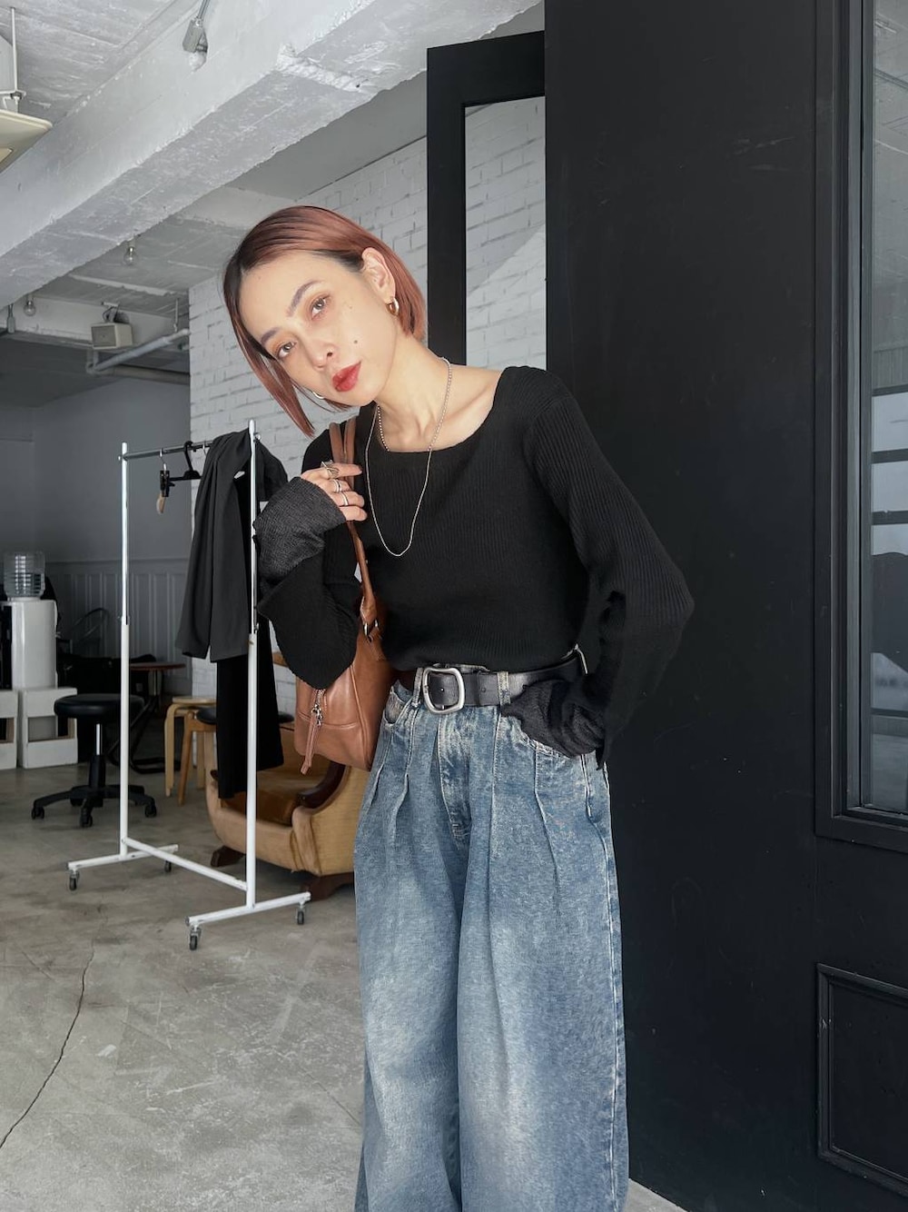 ブラック系のスニーカー、ブルー系のデニムパンツ、イエロー系のボストンバッグを着用したレディースの秋コーディネートの1枚目の写真