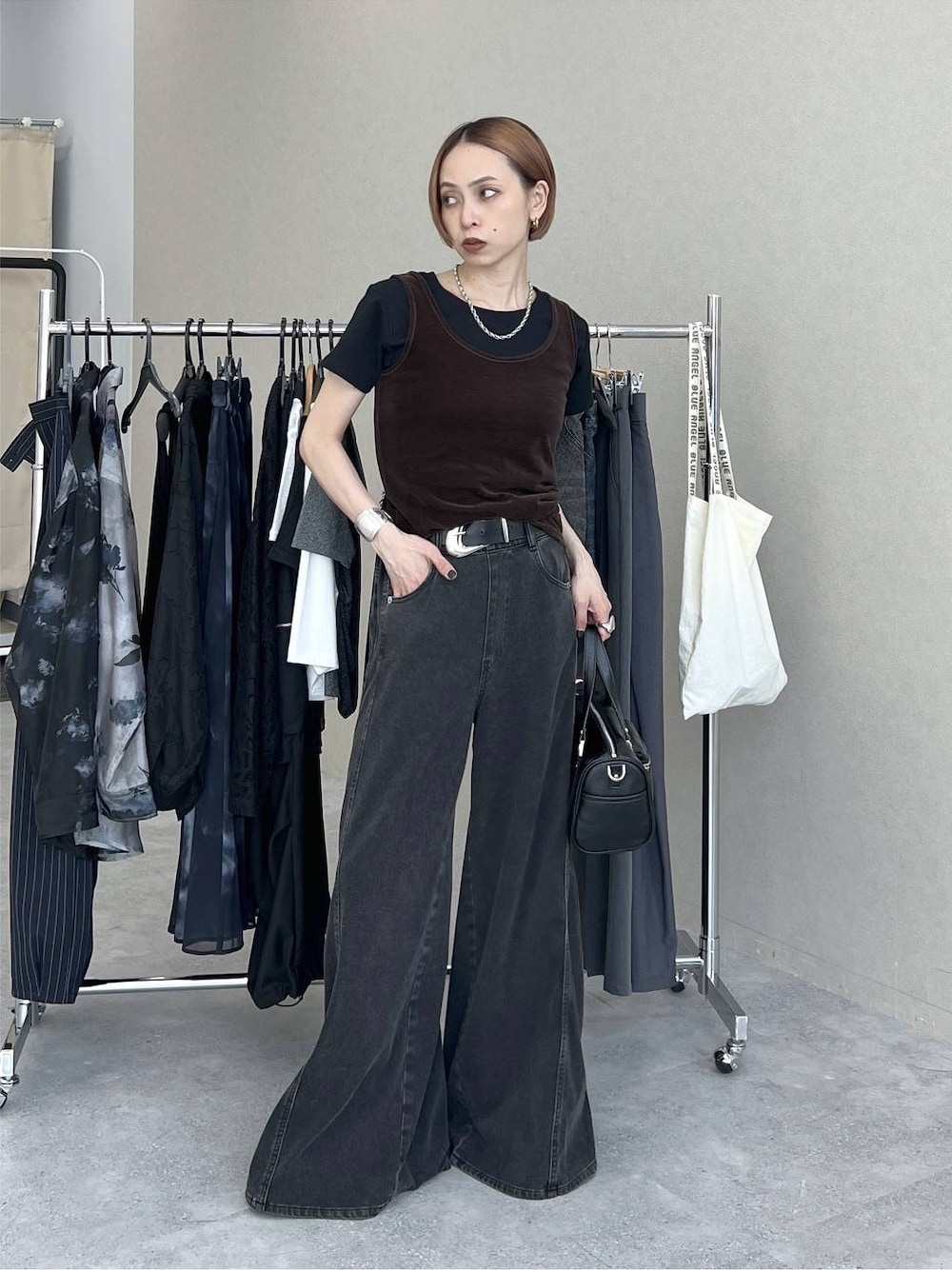 ブラック系のデニムパンツ、ブラック系のショルダーバッグ、ブラウン系のタンクトップを着用したレディースの夏コーディネートの1枚目の写真