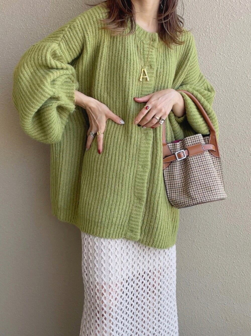 ベージュ系のスカート、グリーン系のカーディガン/ボレロ、ブラウン系のショルダーバッグを着用したレディースの秋コーディネートの1枚目の写真