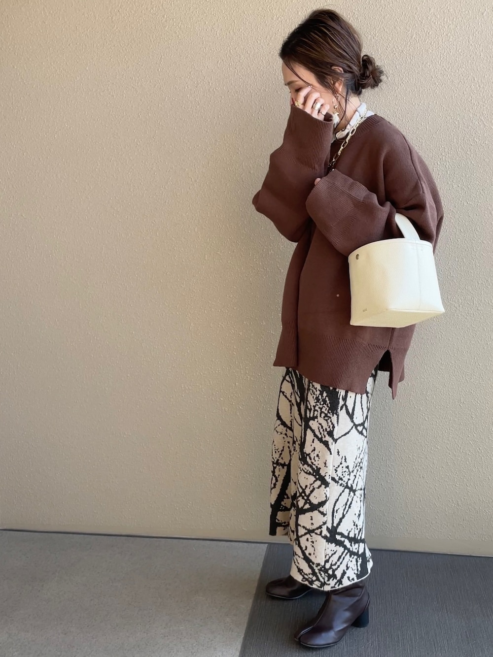 ブラウン系のニット/セーター、ベージュ系のスカート、ベージュ系のその他アウターを着用したレディースの冬コーディネートの1枚目の写真