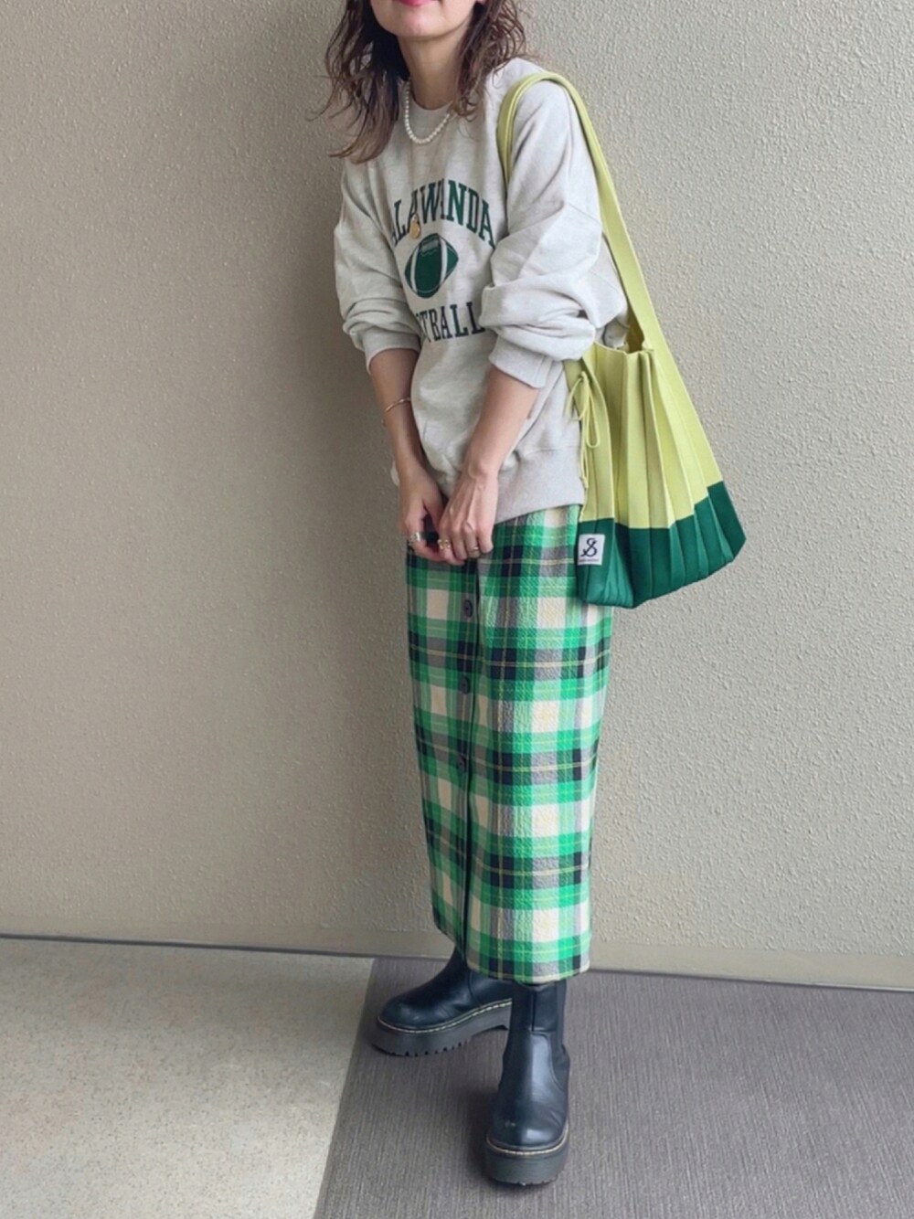 グレー系のスウェット、グリーン系のトートバッグ、グリーン系のスカートを着用したレディースの秋コーディネートの1枚目の写真